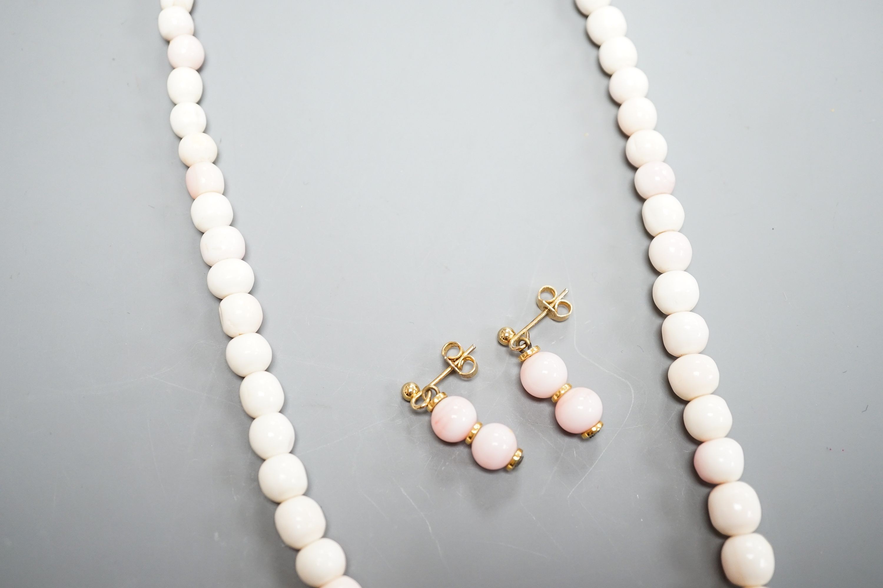 A single strand graduated bleached coral bead necklace, 51cm, gross 43.5 grams and a pair of 750 yellow metal and bleached coral earrings, 24mm, gross 4 grams.